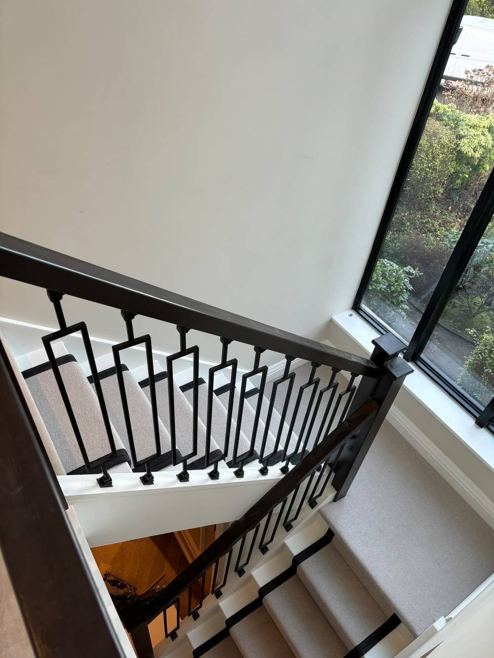 Black balustrade with decorative cut-out spindles on a carpeted staircase