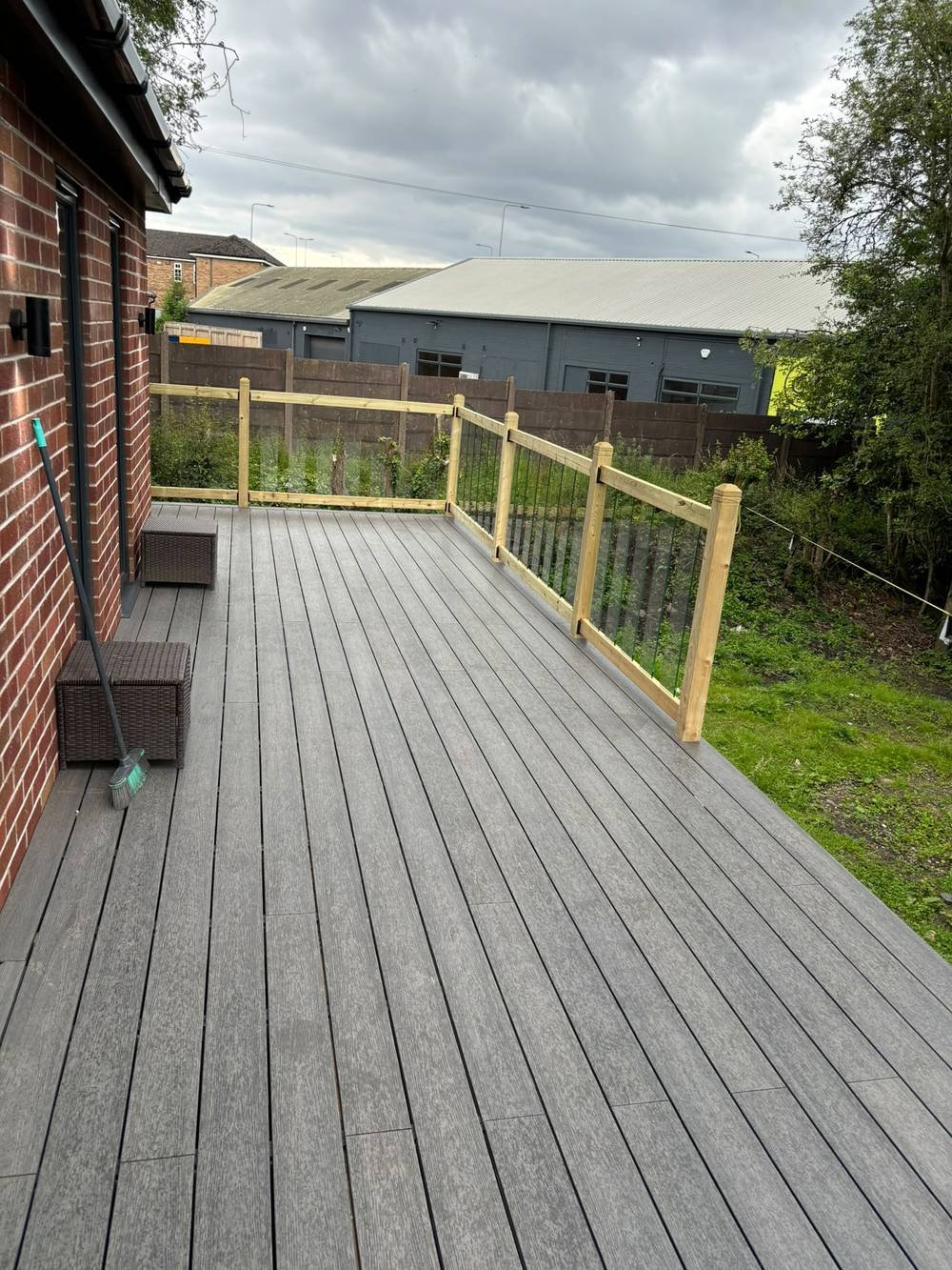 Composite decking with glass balustrade behind a red-brick house