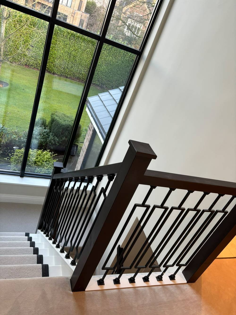 Dark balustrade with decorative cut-out spindles beside a glazed stairwell