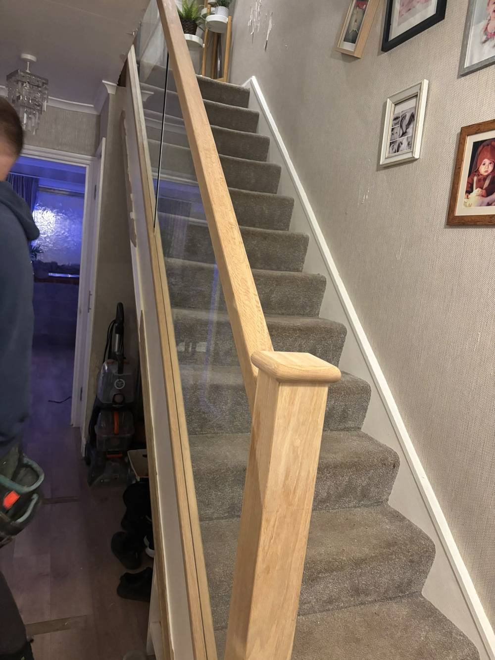 Glass balustrade with oak newel post on a carpeted staircase