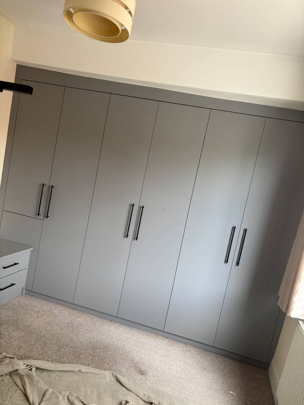 Grey fitted wardrobe wall with black bar handles