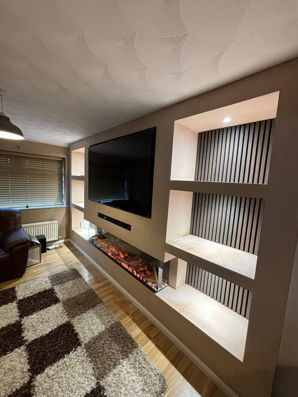 Media wall with slatted alcove shelving, soundbar and recessed fire