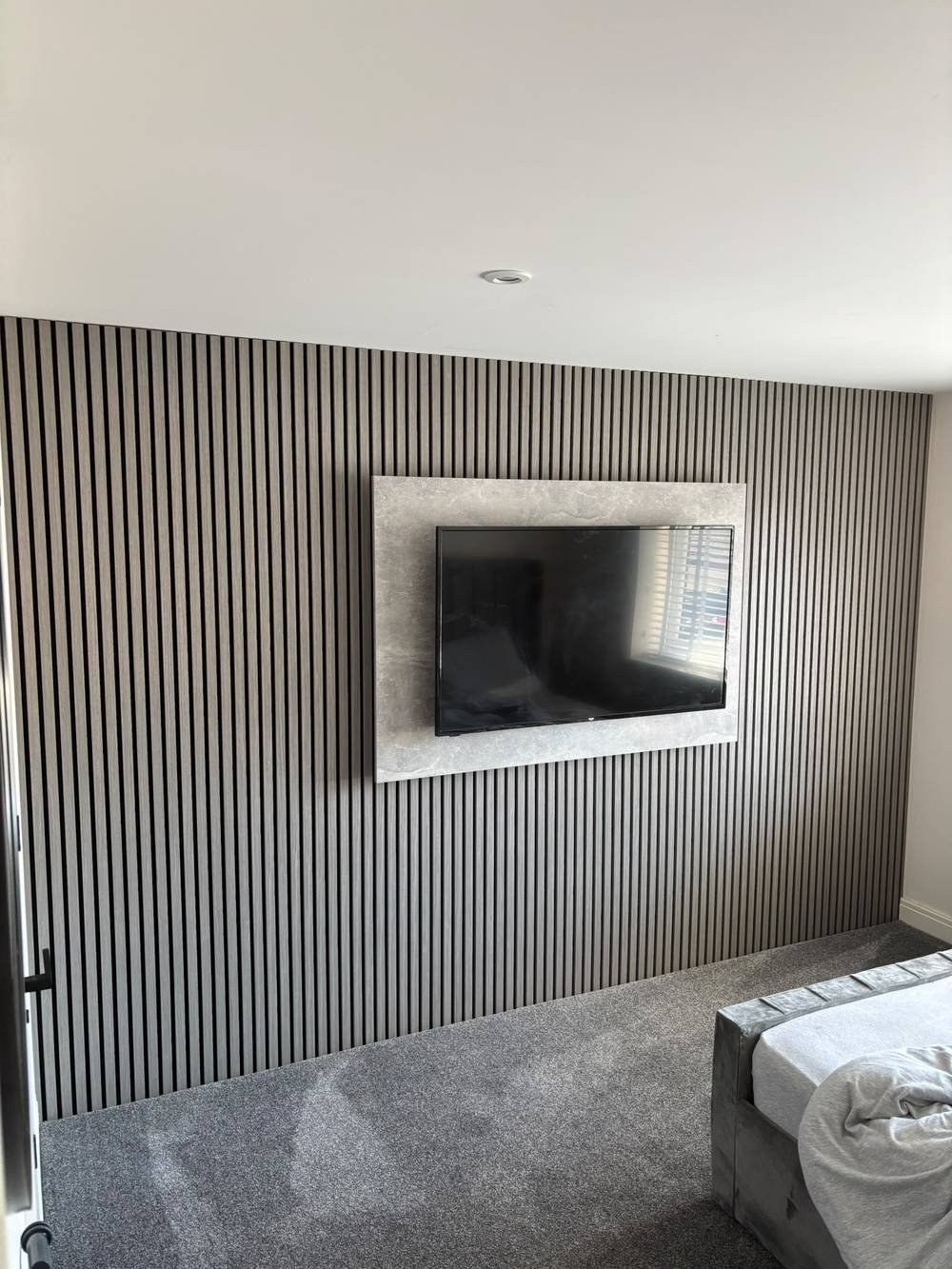 Slatted feature wall with wall-mounted TV on a stone panel