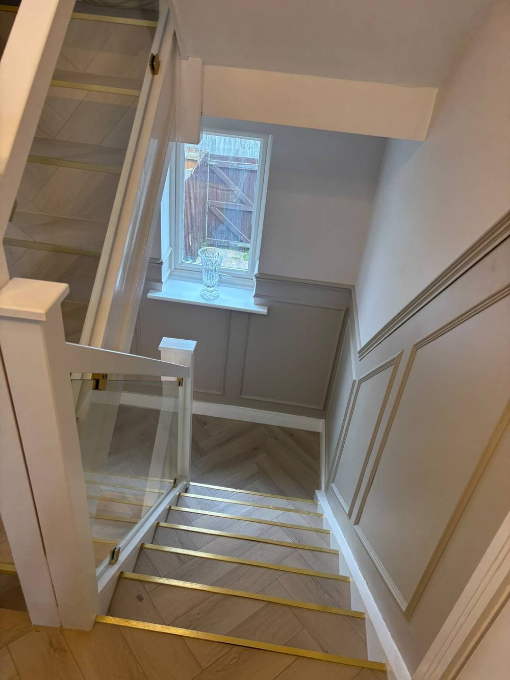Staircase with herringbone flooring and brass stair edging