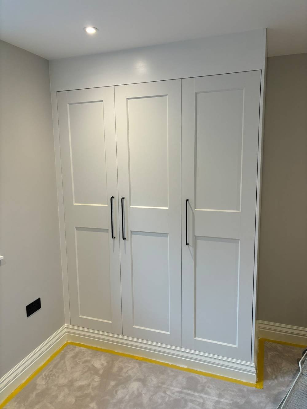 White fitted wardrobe with panelled doors, freshly installed